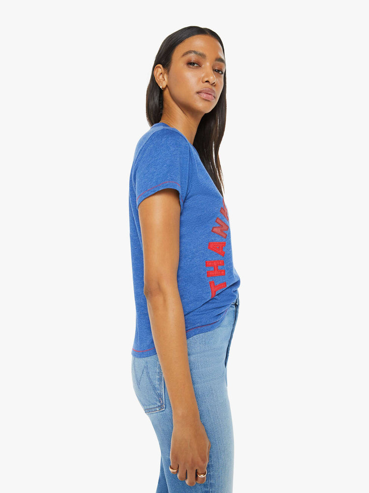 Side view of a woman in a blue tee with mix-matched red patchwork letters on the front that read "Thanks A Lot."