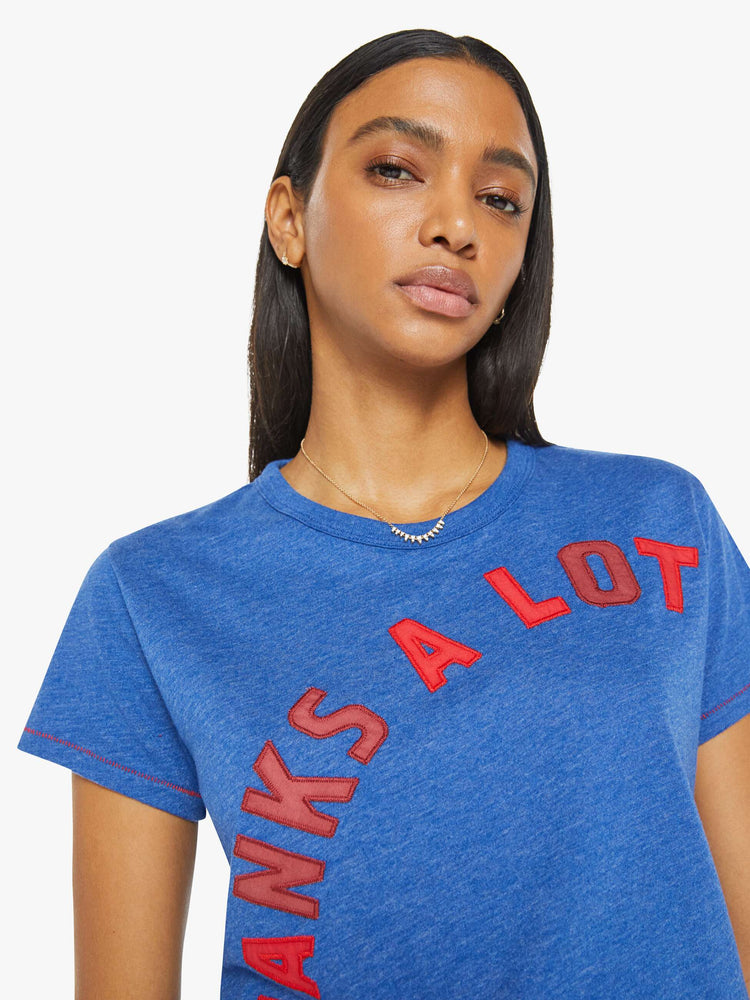 Close up view of a woman in a blue tee with mix-matched red patchwork letters on the front that read "Thanks A Lot."