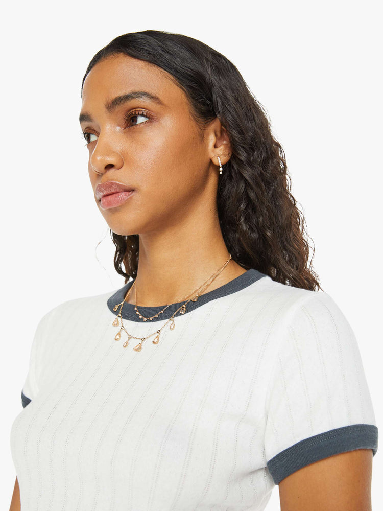 Close up view of a women in a white with navy trim shrunken crewneck tee with extra-short sleeves and a cropped hem.