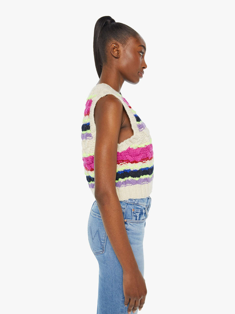 Side view of a woman in a knit sleeveless top with a V-neck and a cropped, ribbed hem in a horizontal stripe pattern with textured knit details.