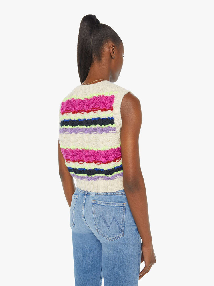 Back view of a woman in a knit sleeveless top with a V-neck and a cropped, ribbed hem in a horizontal stripe pattern with textured knit details.