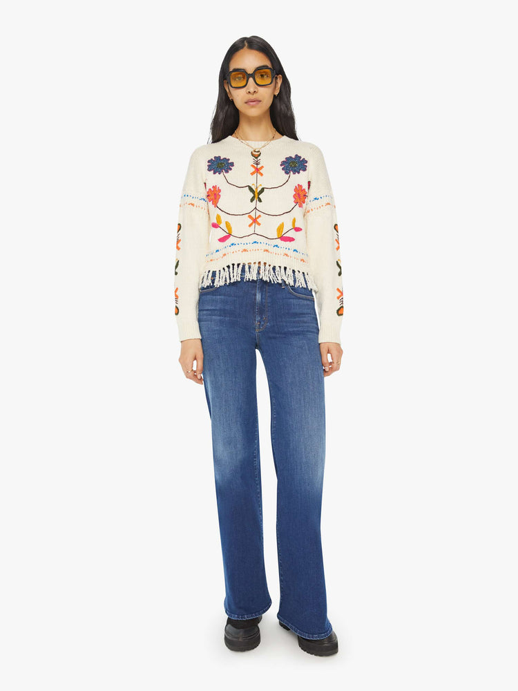 Full front view of a woman in an off-white cropped crewneck sweater with hand-embroidered flowers, drop shoulders and a cropped, fringed hem.