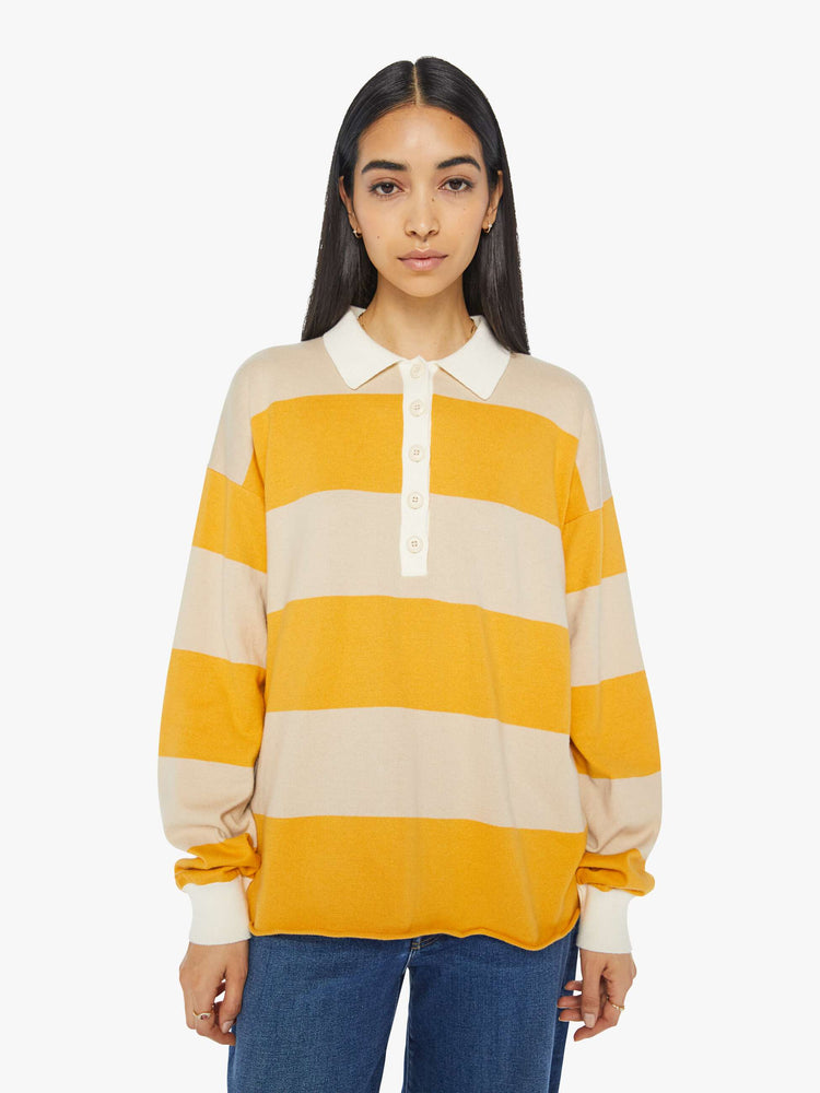 Front view of a woman polo  with drop shoulders, extra-long sleeves, a loose, oversized fit and a raw hem in a cream and yellow horizontal stripes.