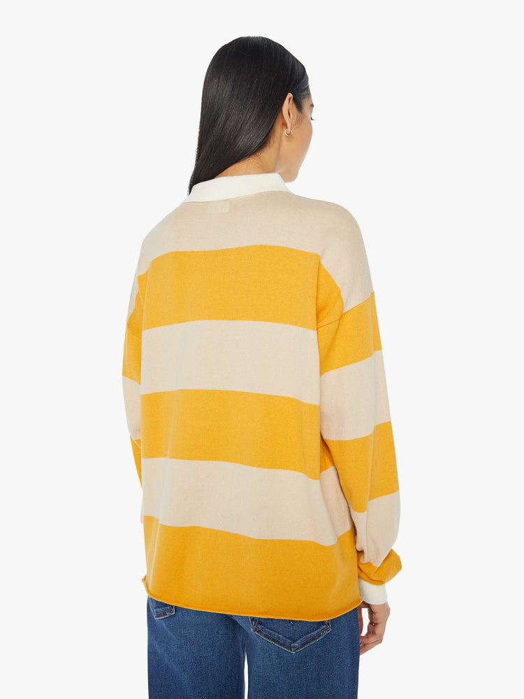 Back view of a woman polo  with drop shoulders, extra-long sleeves, a loose, oversized fit and a raw hem in a cream and yellow horizontal stripes.