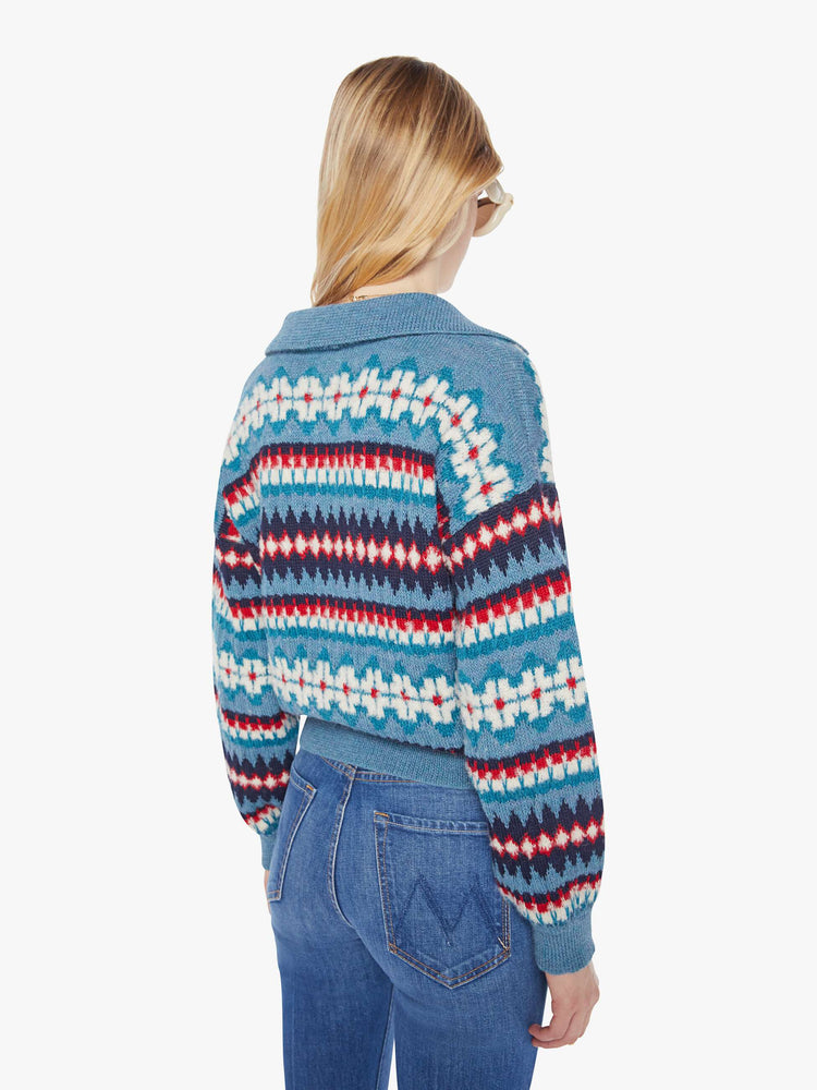 Back view of a woman in a light blue with red and navy details cropped sweater with a collared V-neck that laces and ties, drop shoulders, ribbed hems and a loose fit.