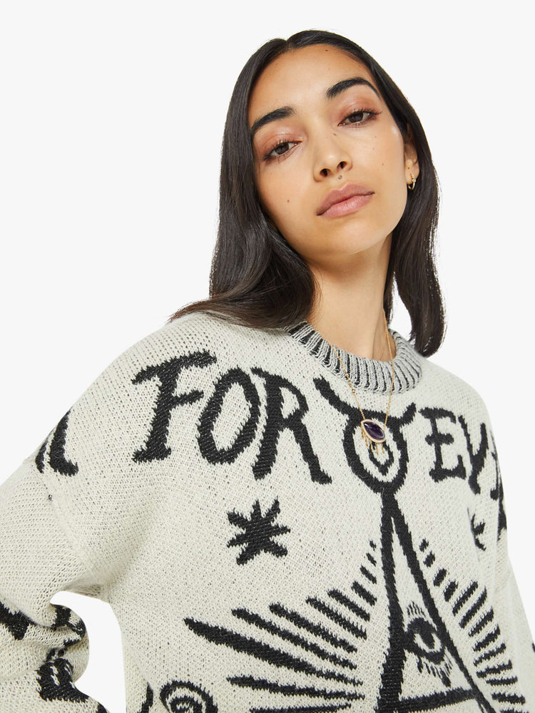 Close up view of a woman in a crewneck sweater in a heathered grey with mystic graphics and text in black.