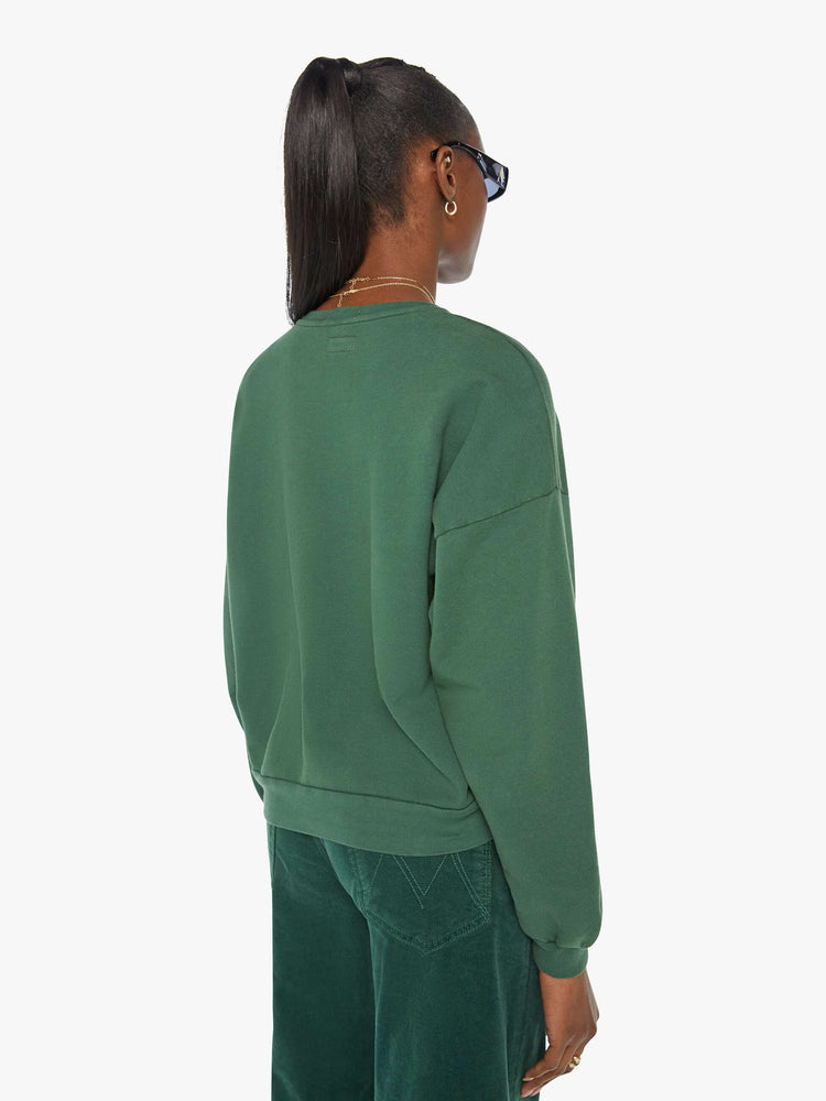 Back view of a woman in a green crewneck sweatshirt designed with a puff-paint graphic sun, butterfly and leaves on the front.