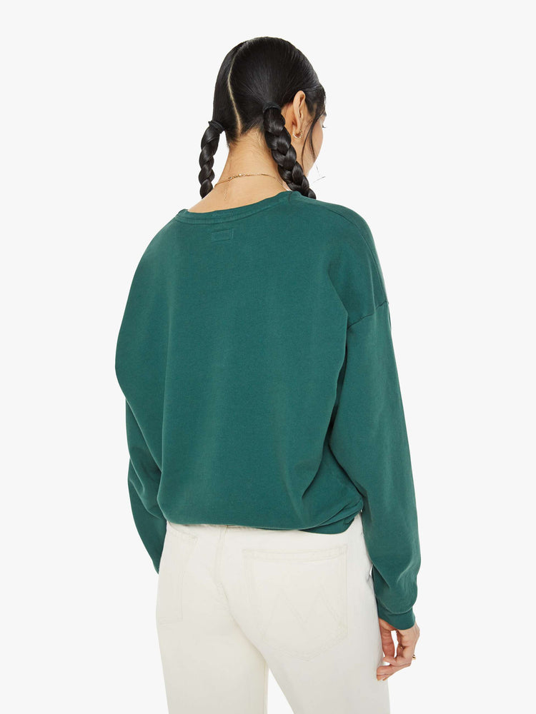 Back view of a woman in a green sweatshirt dropped sleeves and a relaxed fit.