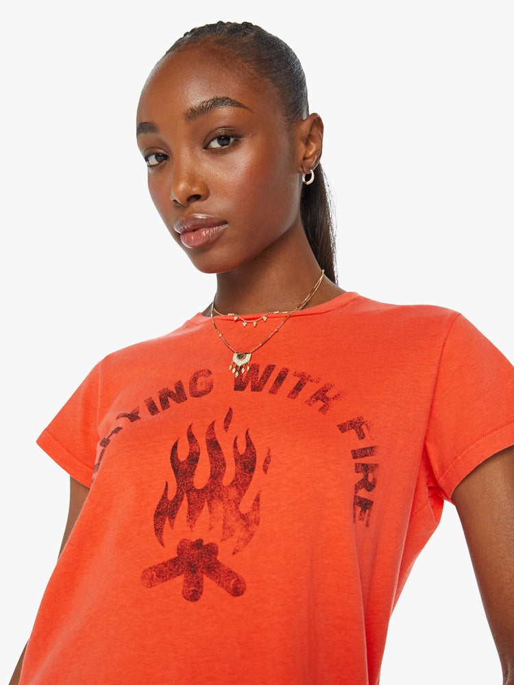 Detailed view of a woman in an orange crewneck with a slim designed with a faded graphic on the front.