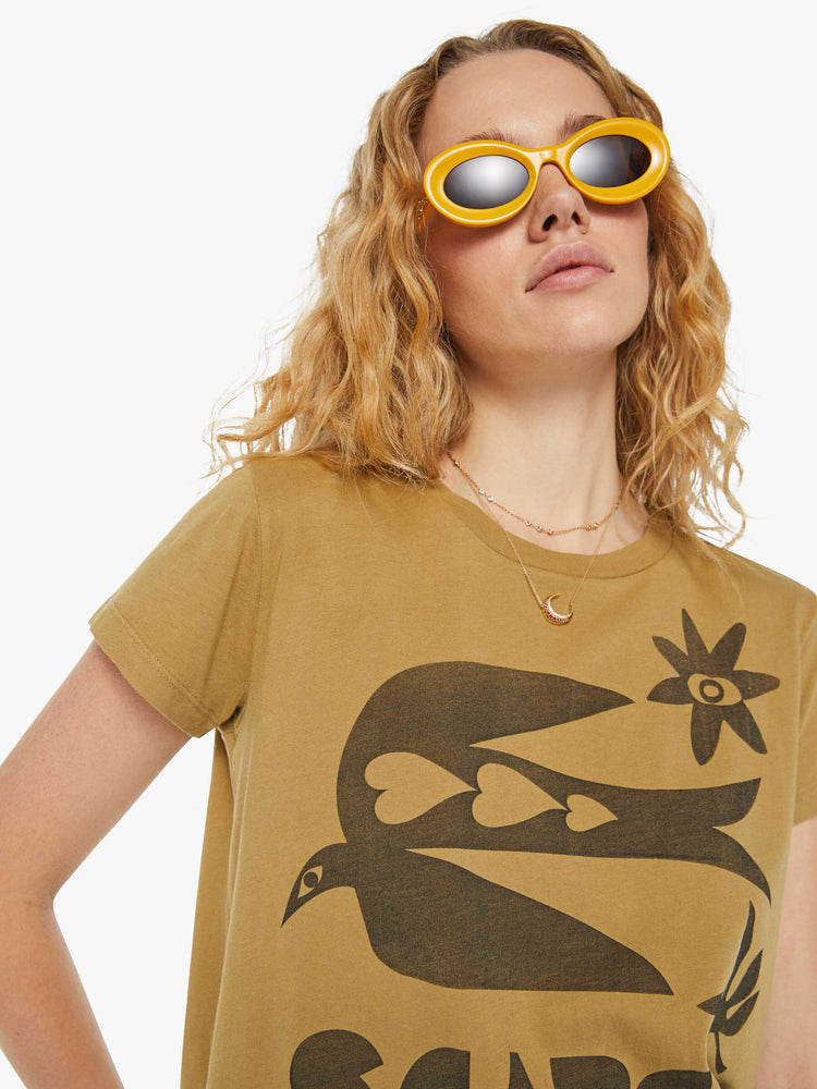 Detailed view of a woman in a mustard yellow crewneck tee with a slim fit that has a faded black bird graphic with text on the front.