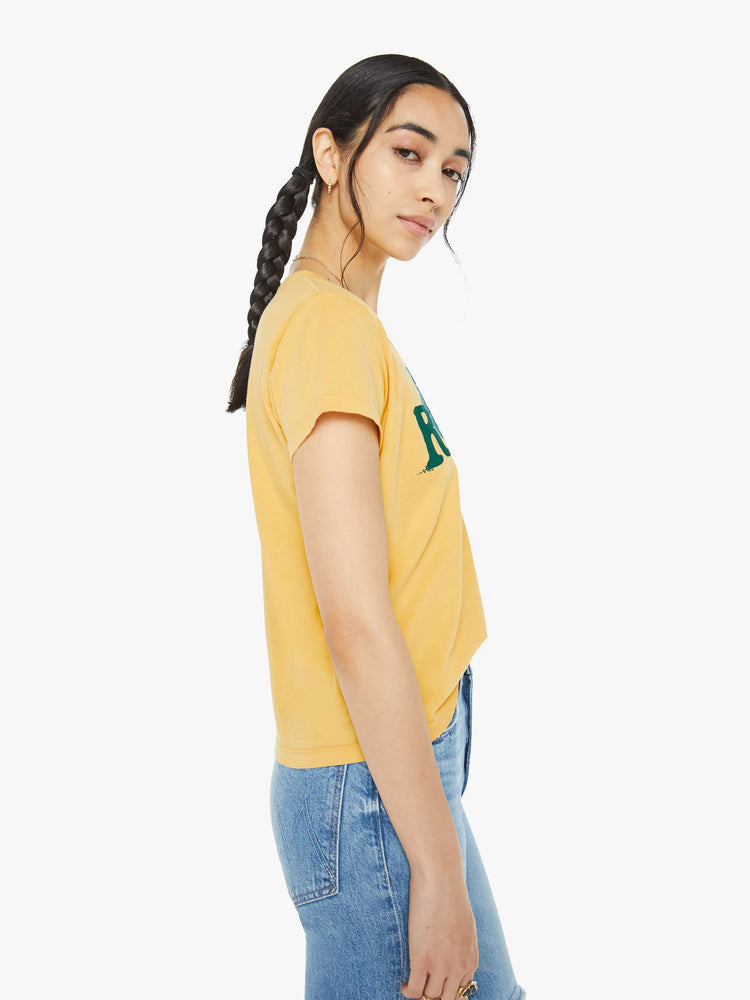 Side view of a woman in a yellow tee features a blue and green text graphic on the front.