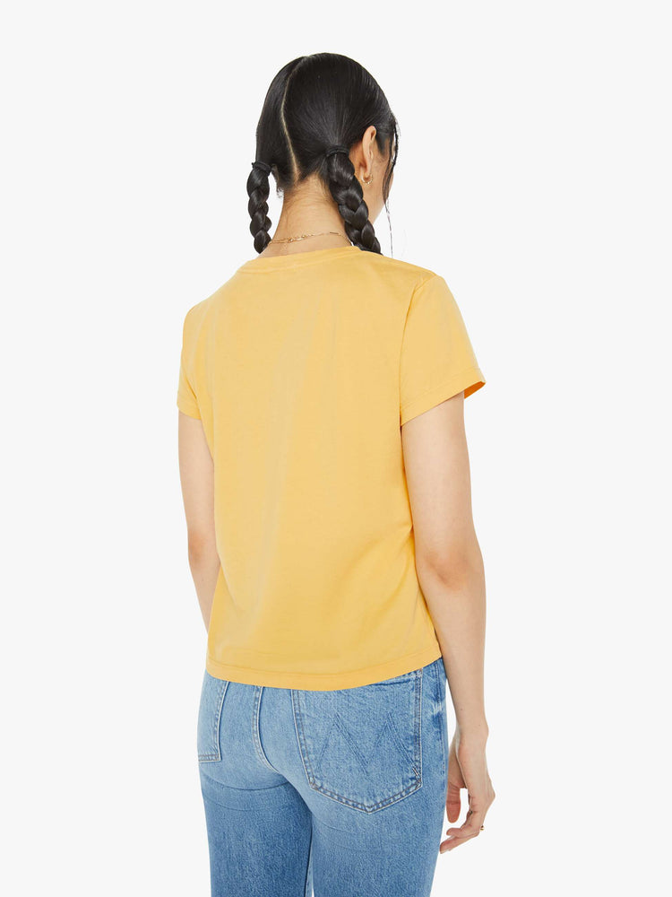 Back view of a woman in a yellow tee features a blue and green text graphic on the front.