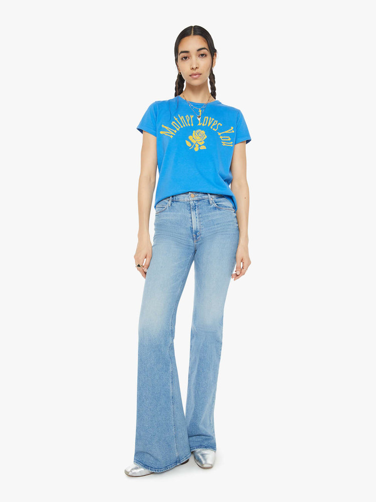 Full body view of a woman blue tee with a message from MOTHER and a yellow rose on the front.