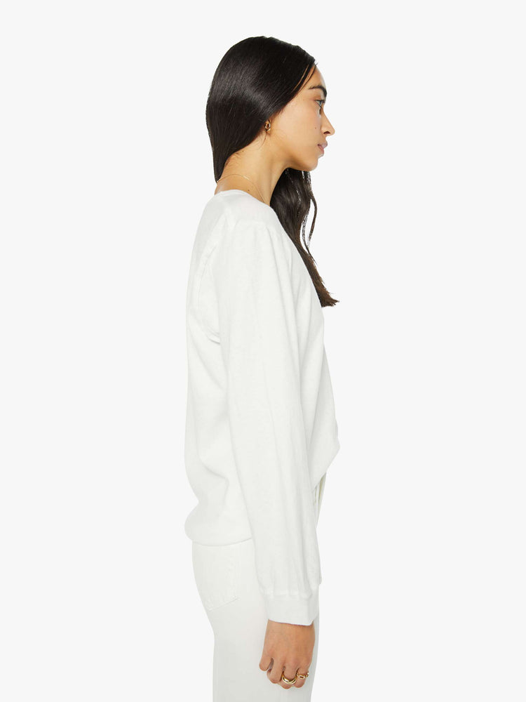 Side  view of a woman crewneck tee with long sleeves and an oversized fit in a bight white hue.