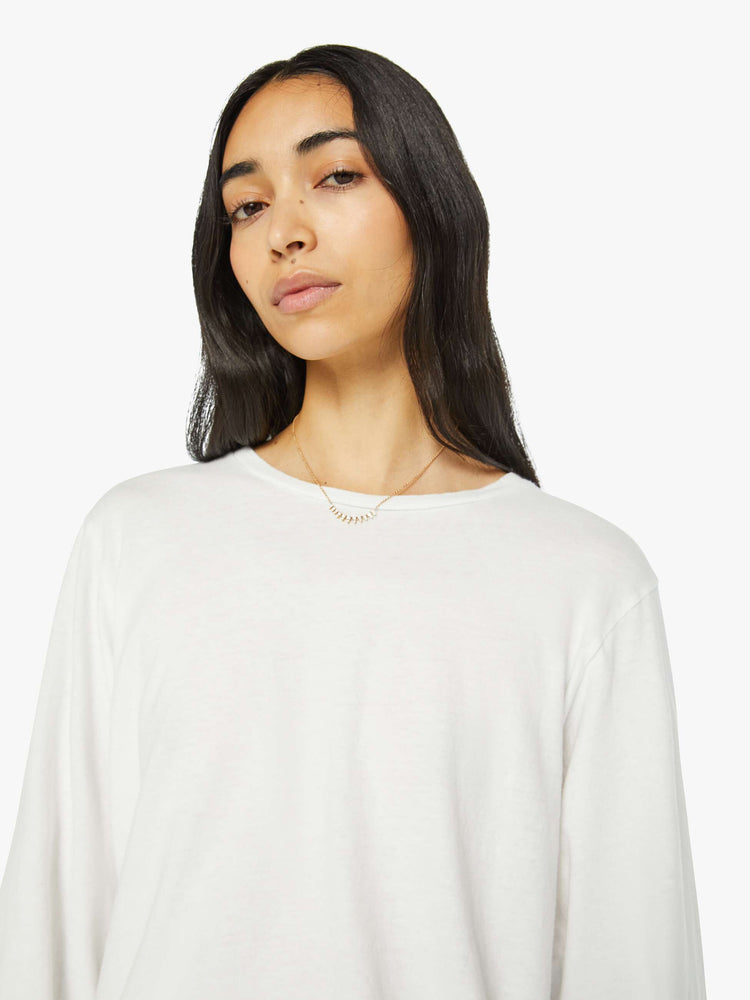 Close up  view of a woman crewneck tee with long sleeves and an oversized fit in a bight white hue.