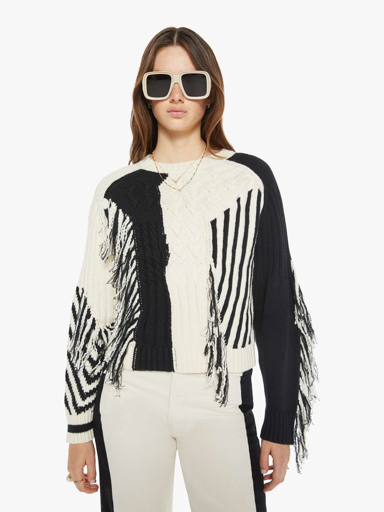 Front view of a woman crewneck sweater with drop shoulders, ribbed hems and a cropped, boxy fit in a cream and black geometric panels and fringe details.