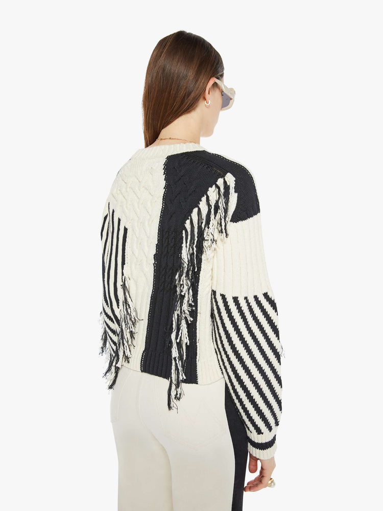 Back view of a woman crewneck sweater with drop shoulders, ribbed hems and a cropped, boxy fit in a cream and black geometric panels and fringe details.