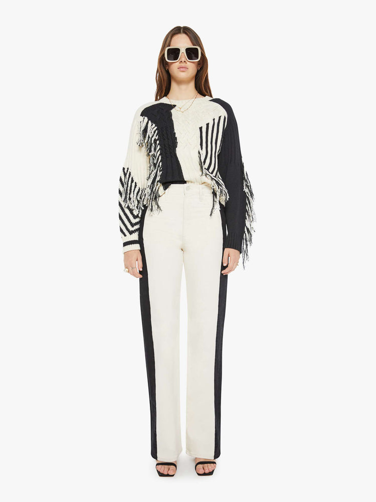 Full body view of a woman crewneck sweater with drop shoulders, ribbed hems and a cropped, boxy fit in a cream and black geometric panels and fringe details.