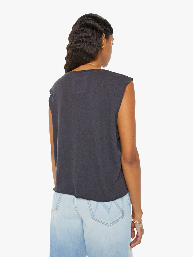 Back view of a woman in a faded black slightly sheer crewneck with chopped sleeves and a slim fit.