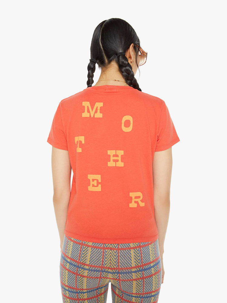 Back view of a woman in a bright orange-red tee features a blue roadrunner graphic with text on the front and MOTHER's name in yellow on the back.