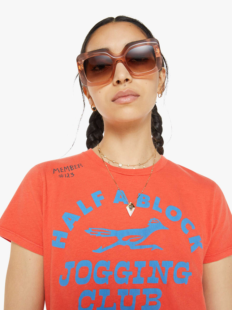 Up close view of a woman in a bright orange-red tee features a blue roadrunner graphic with text on the front and MOTHER's name in yellow on the back.