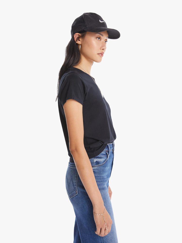 A side view of a woman wearing a fitted black crew neck tee, paired with a pair of medium blue wash jeans.