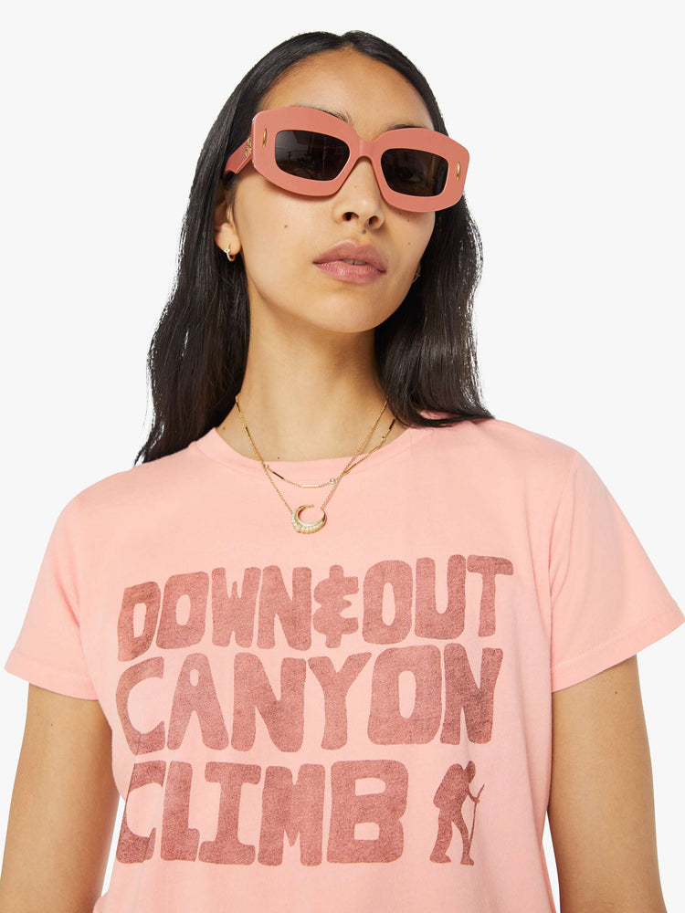 Detailed view of a woman in a sheer baby pink crewneck tee with a slim fit featuring a faded text graphic on the front.