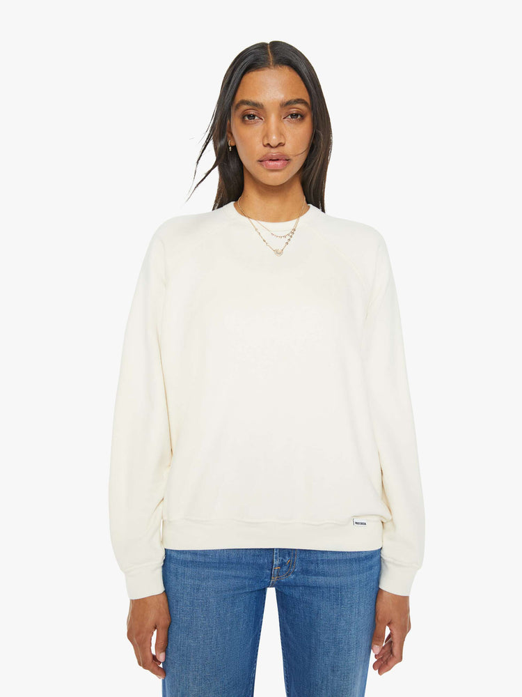 Front view of a woman in a cream oversized raglan sweatshirt with a crewneck, ribbed hems and a slightly cropped fit.