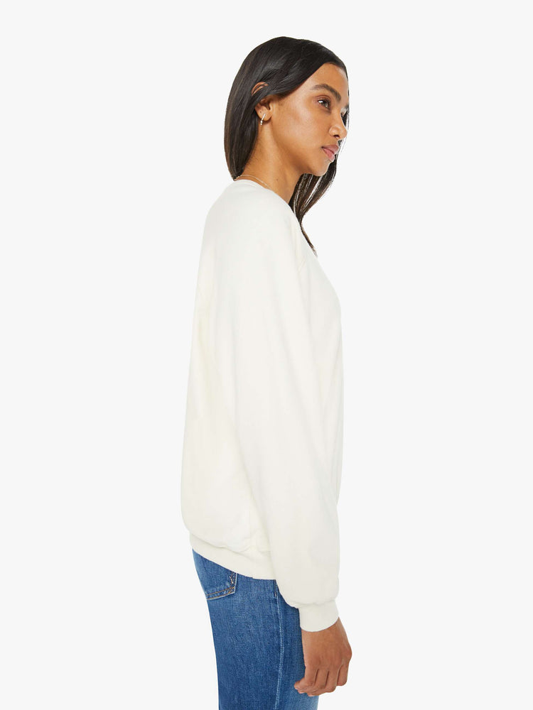 Side view of a woman in a cream oversized raglan sweatshirt with a crewneck, ribbed hems and a slightly cropped fit.