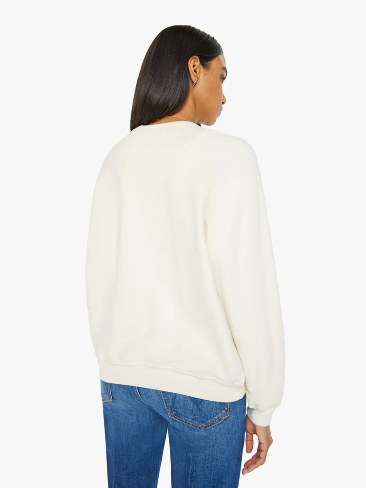 Back view of a woman in a cream oversized raglan sweatshirt with a crewneck, ribbed hems and a slightly cropped fit.