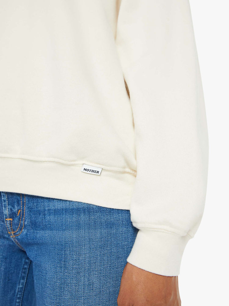 Close up view of a woman in a cream oversized raglan sweatshirt with a crewneck, ribbed hems and a slightly cropped fit.