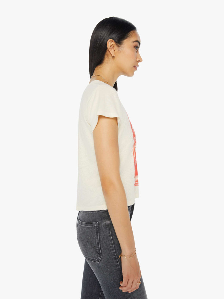 Side view of a woman in a cream tee with a faded red graphic of Mount Everest on the front.