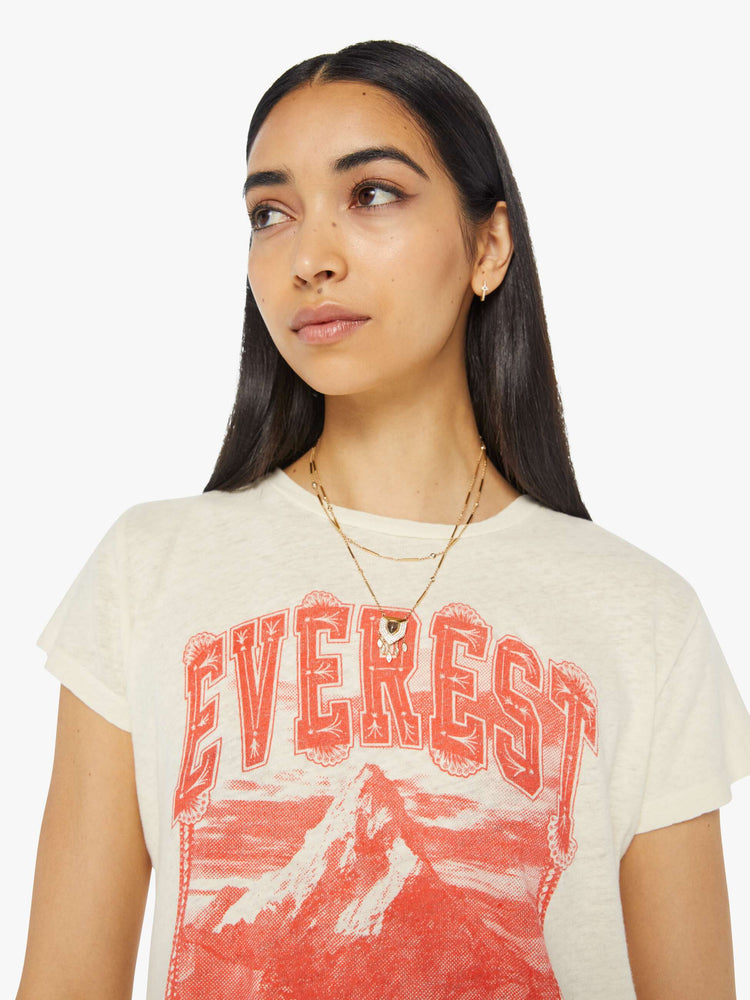 Close up view of a woman in a cream tee with a faded red graphic of Mount Everest on the front.