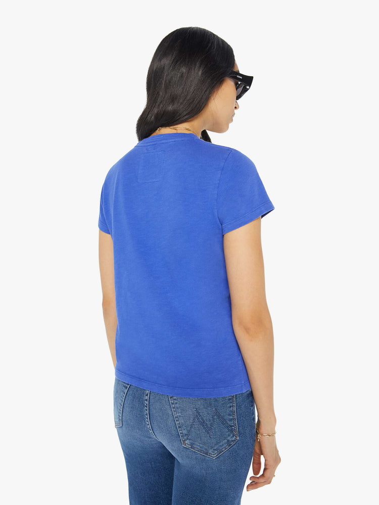 Back view of a woman in a blue crewneck tee with a faded graphic with text in yellow on the front.