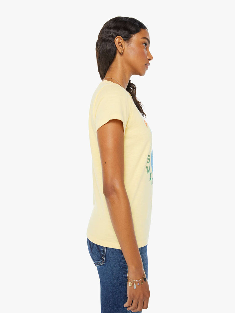 Side view of a woman crewneck with a slim fit in a pastel yellow with a mermaid graphic with text in orange and green on the front.