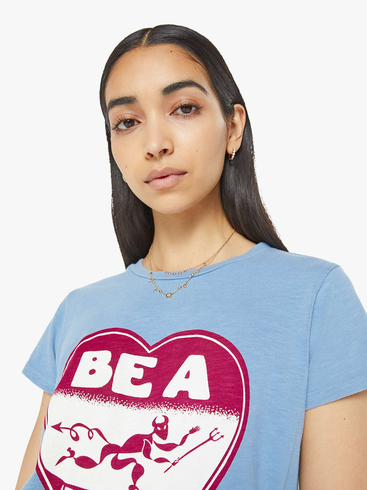 Close up view of a woman in a sky blue color tee with a maroon heart graphic with text on the front.