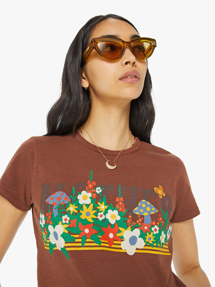 Detailed view of a woman in a brown crewneck tee with a slim fit featuring a colorful garden bed graphic on the front.