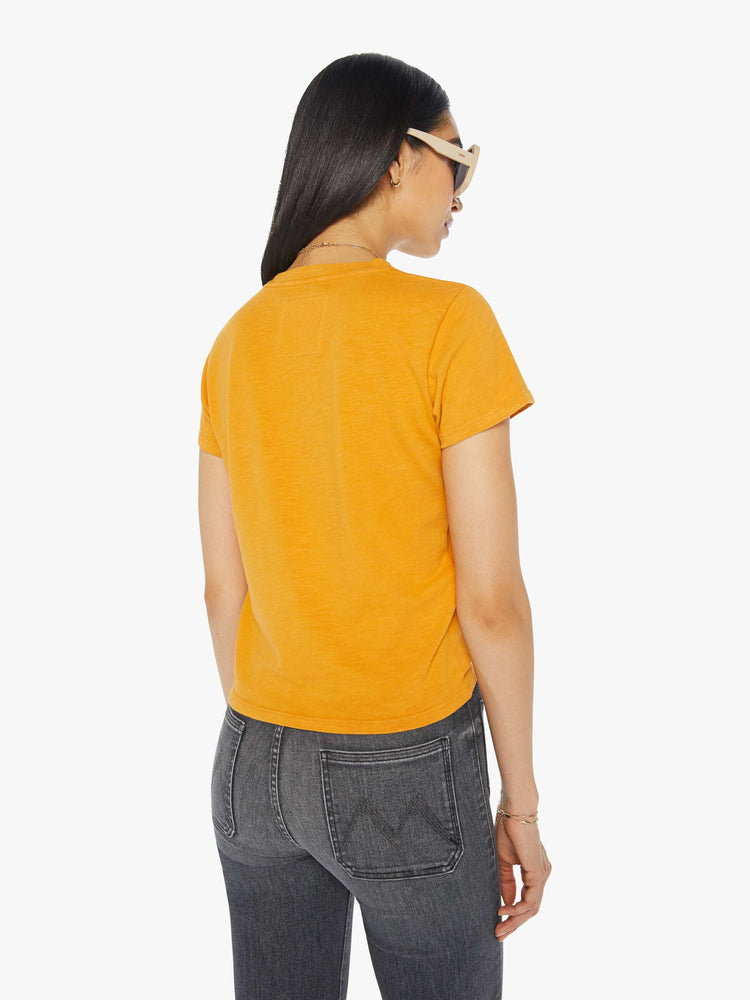 Back view of a woman in an orange tee with faded text graphic in red.