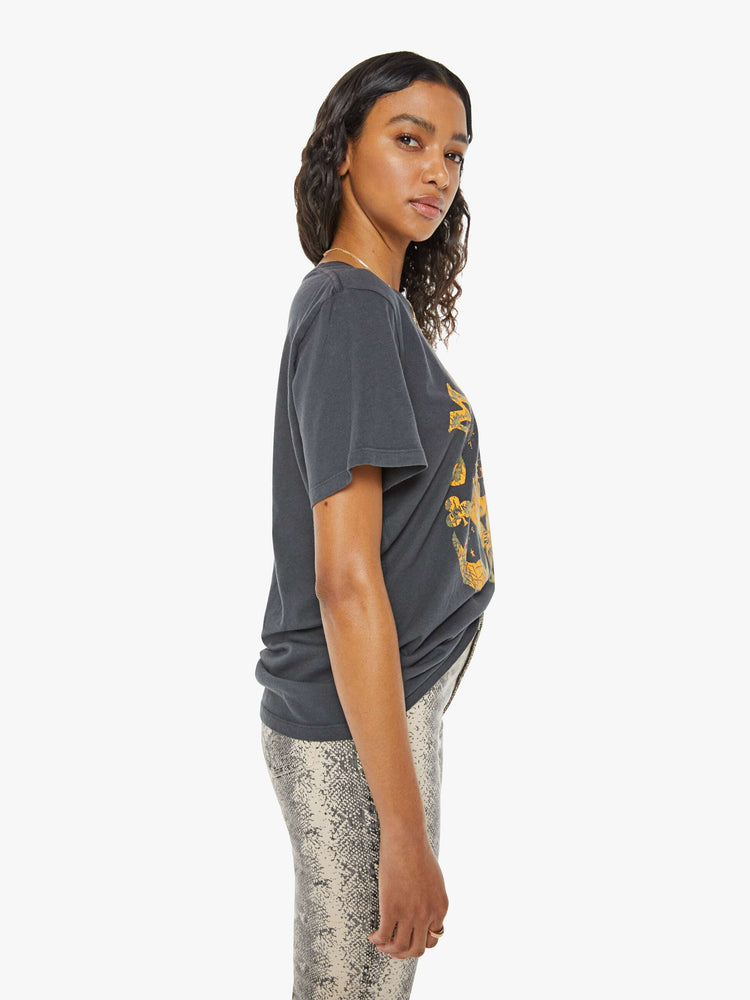 Side view of a woman in a black tee with a golden yellow graphic and MOTHER's name on the front.