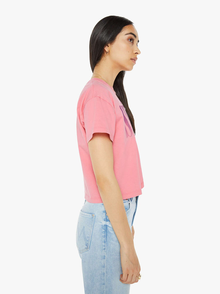 Side view of a pink oversized crewneck tee with drop shoulders, a cropped hem and a boxy fit and purple print.