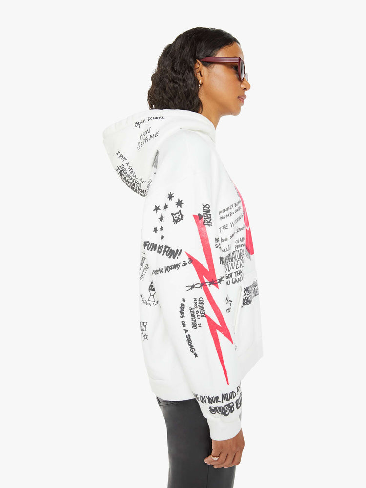 Side view of a woman in a classic hoodie with drop shoulders, a front patch pocket and ribbed hems in white  and red smiley face with drawn scribbles.