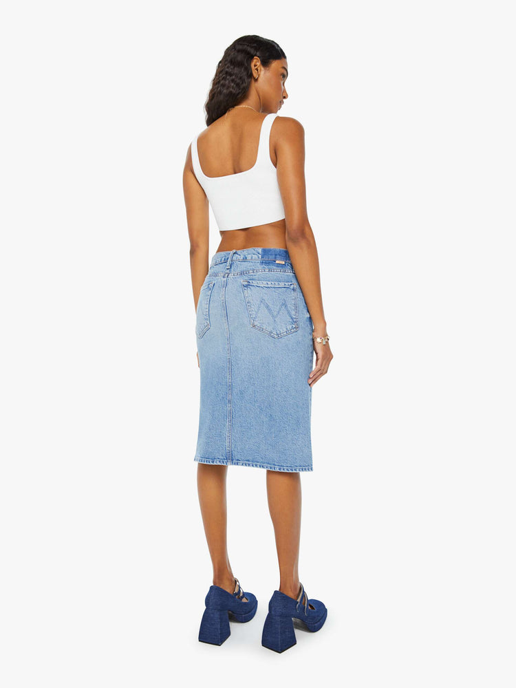 Back view of a woman in light blue denim midi skirt with a button fly and relaxed fit that's designed to sit on the hips. 