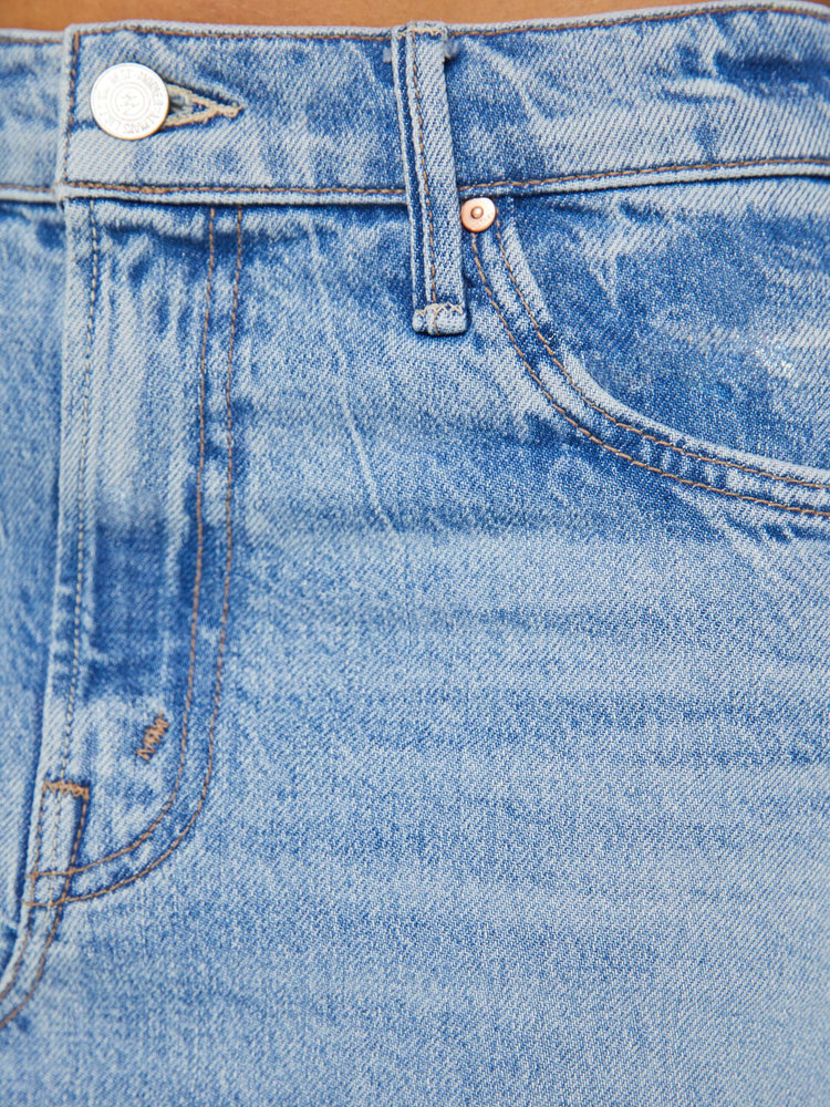 Detailed view of a woman in light blue denim midi skirt with a button fly and relaxed fit that's designed to sit on the hips. 