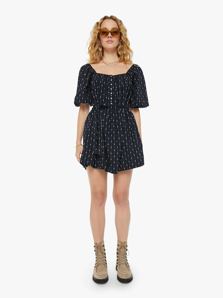 Front view of a woman  square neck mini dress with elbow-length balloon sleeves, buttons down the chest, an elastic waistband and a thigh-grazing hem in black with white stripes and polda dots.