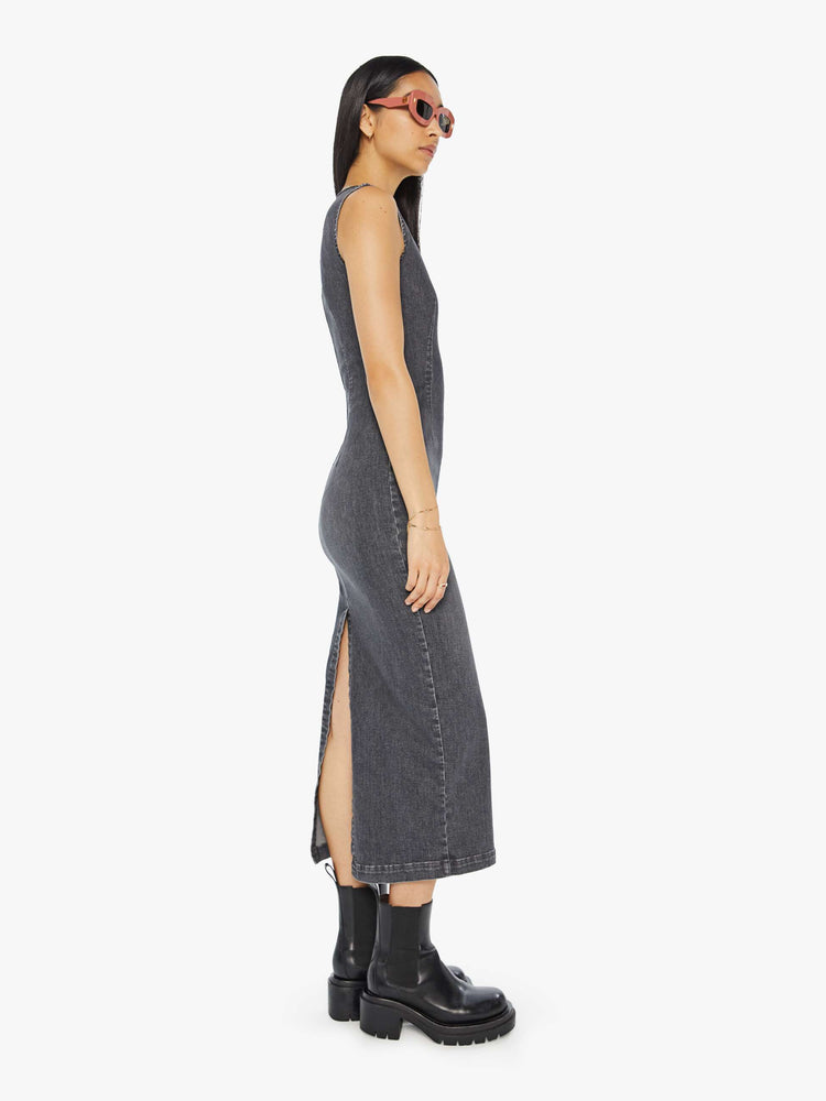 Side view of a woman in a dark grey  sleeveless denim midi dress with a crewneck, seamed details and a narrow fit. 