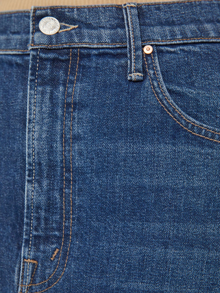 Detailed view of a woman in a dark blue denim maxi skirt with a high rise, thigh-high front slit and a floor-length hem.