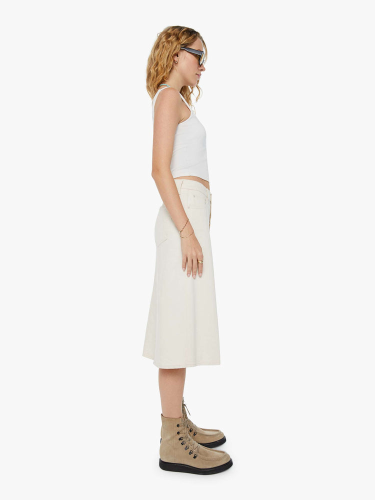 Side view of a woman in a creamy white low-rise skirt with a slouchy A-line fit and a front slit. 