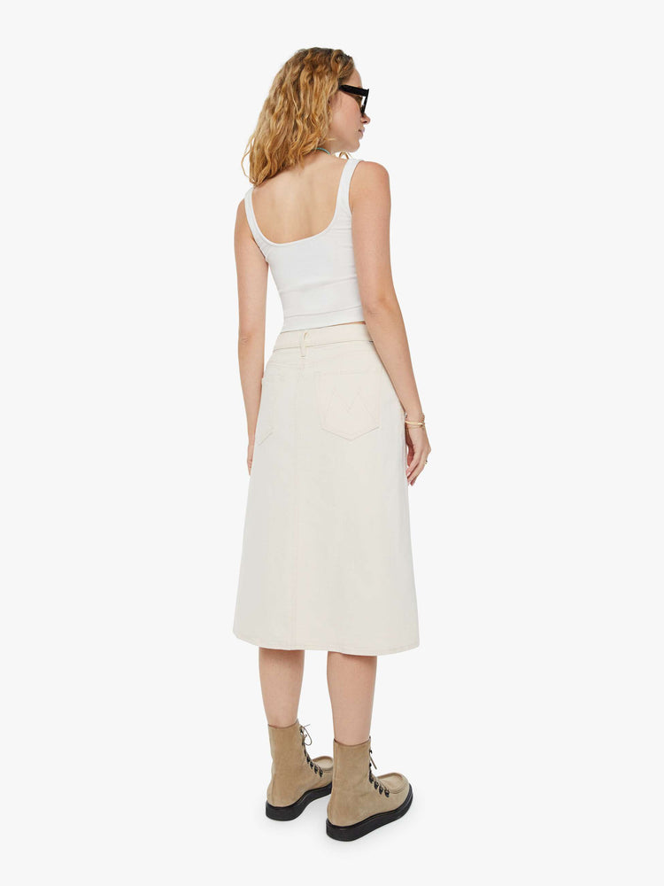 Back view of a woman in a creamy white low-rise skirt with a slouchy A-line fit and a front slit. 