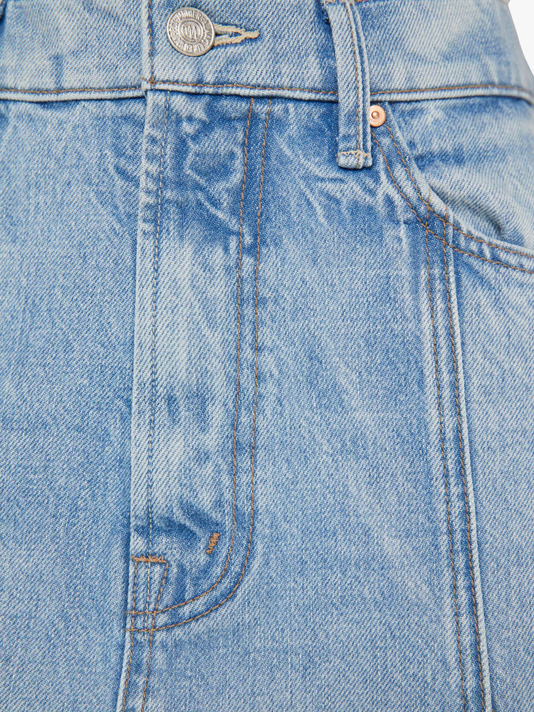 Swatch view of a woman in a high waisted denim midi skirt with slit pockets, seamed details down the front and raw hem in light blue denim.