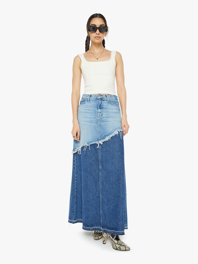 Front view of a woman in denim maxi skirt with a button fly, frayed hem and relaxed fit that's designed to sit on the hips in half light blue and half mid blue.